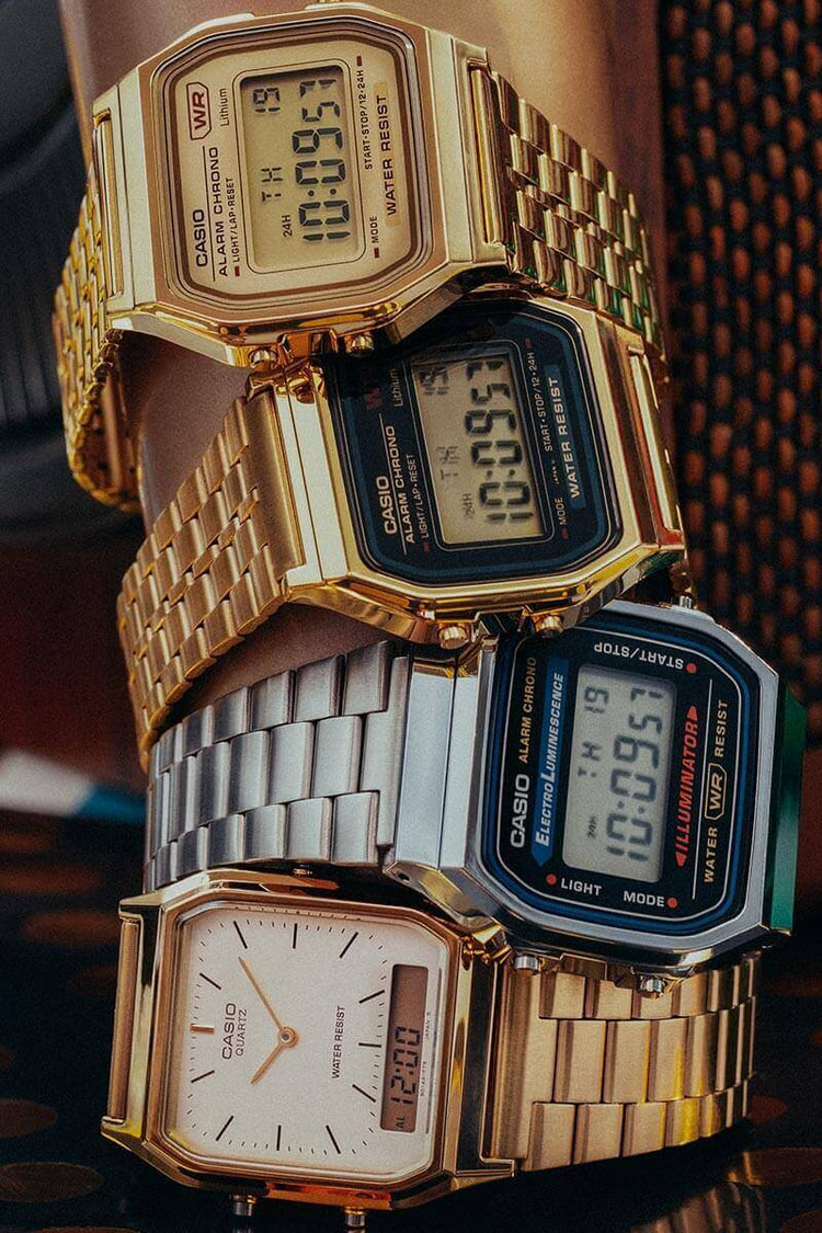 Vier casio vintage horloges op elkaar gestapeld, drie gouden en een zilverkleurig horloge. Digitale display.