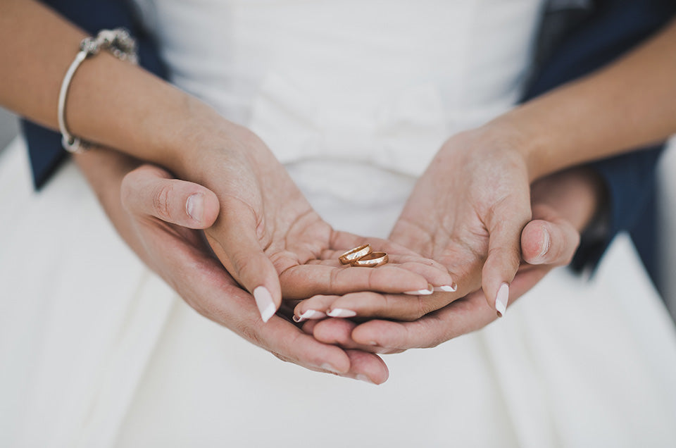 koppel houdt hun duo trouwringen samen in hun hand